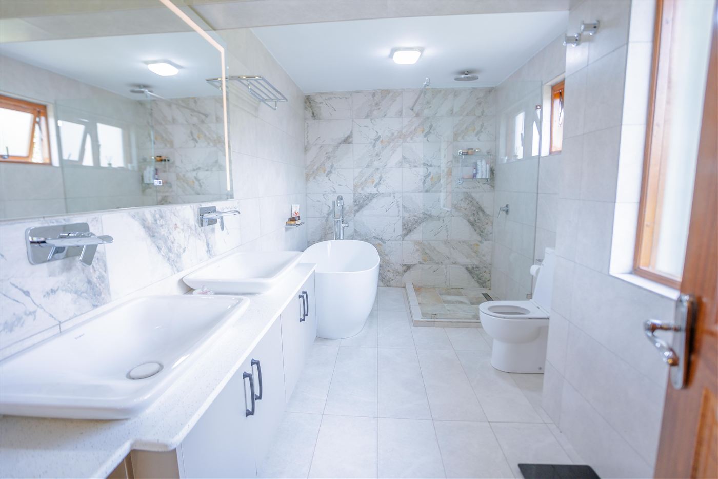 Full ensuite bathroom with double vanity, freestanding tub and glass shower