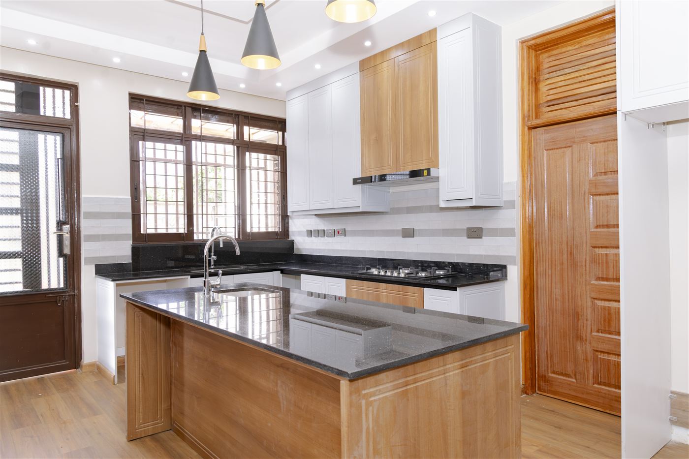 Full kitchen view with pendant lighting, gas hob and timber door