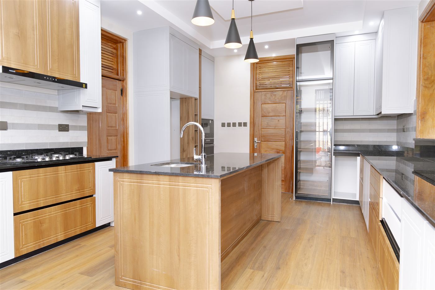Open-plan kitchen with wood and white cabinetry, black granite island