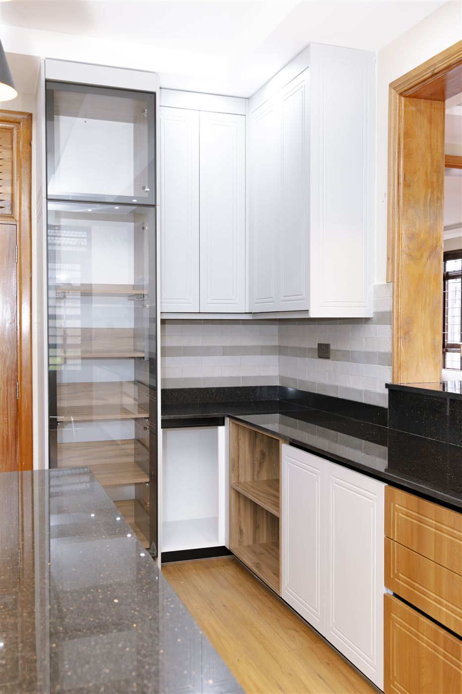 Kitchen pantry with glass-front cabinetry and black granite counter